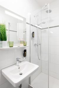 uma casa de banho branca com um lavatório e um chuveiro em Hotel Hamm em Weiterstadt