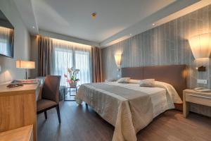 a bedroom with a bed and a desk and a chair at Hotel Harrys' Garden in Abano Terme