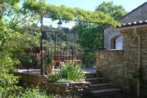a garden with a stone fence and a gate at La maison jaune in La Roque-sur-Pernes