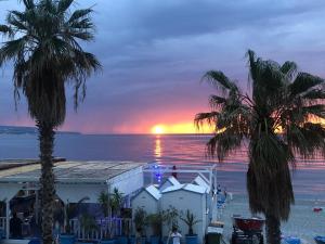 a sunset over the ocean with palm trees at Mareblù in Scilla