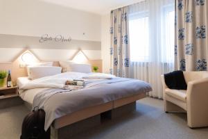 a bedroom with a bed and a chair and a window at Hotel Hamm in Weiterstadt