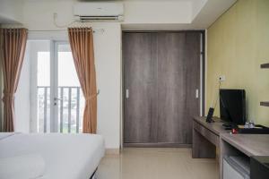 a bedroom with a white bed and a sliding door at Cozy and Sweet Studio at Paramount Skyline Apartment By Travelio in Tangerang
