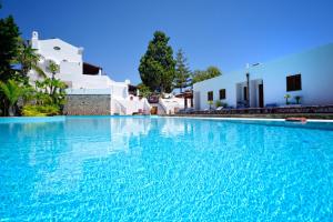 une grande piscine d'eau bleue devant des bâtiments blancs dans l'établissement Gattopardo Park Hotel, à Lipari