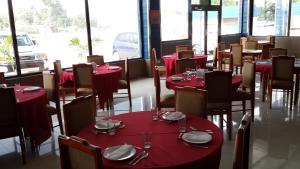 un comedor con mesas y sillas rojas y ventanas en Express Inn Coronado & Camping, en Playa Coronado