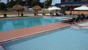 a large swimming pool with chairs and umbrellas at Express Inn Coronado & Camping in Playa Coronado