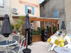 un patio con sillas, mesas y sombrillas en L'Auberge Chez Pascal en Saint-Julien-de-Cassagnas