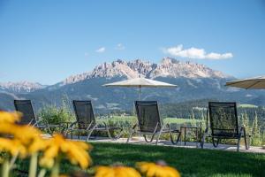 a group of chairs and umbrellas with mountains in the background at Panoramahotel Obkircher in Nova Ponente