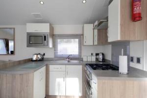 uma cozinha com armários brancos e um forno com placa de fogão em Edinburgh - Seton Sands - Rio Caravan - Pet Friendly em Edimburgo