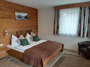 a bedroom with a bed and a chair and a window at Pension Ballwein in Salzburg