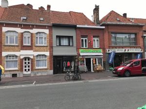 ein rotes Auto, das vor Gebäuden auf einer Straße geparkt ist in der Unterkunft Duplex tout confort Menen in Menen