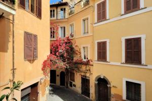 un callejón entre dos edificios con flores rojas en Bollo, en Roma