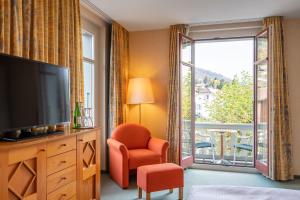 a living room with a television and a large window at Schönbühl Hotel & Restaurant Lake Thun in Thun