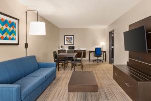 uma sala de estar com um sofá azul e uma mesa em Holiday Inn Express Hotel & Suites Fort Myers East - The Forum, an IHG Hotel em Fort Myers