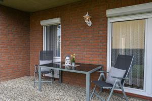 a table and chairs on a patio next to a brick wall at Haus Meeresglück Seeigel in Dahme