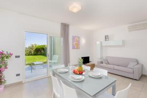 un soggiorno bianco con tavolo e sedie di Villa Marconi Apartment 4 a Golfo Aranci