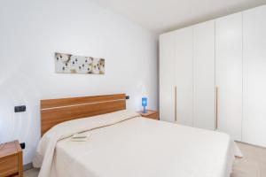 una camera da letto con un letto bianco con testiera in legno di Villa Marconi Apartment 4 a Golfo Aranci