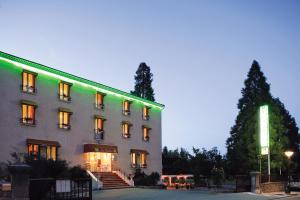 Un bâtiment avec des lumières vertes sur son côté dans l'établissement Logis Hôtel Restaurant Les Cèdres, à Joyeuse