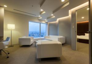 Habitación con muebles blancos y ventana grande. en Daiwa Roynet Hotel Numazu, en Numazu