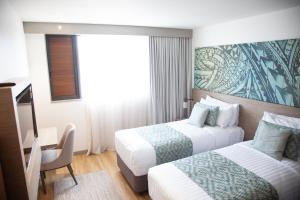 Cette chambre comprend deux lits et un bureau. dans l'établissement Lava Hotel, à Apia