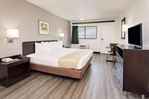 a hotel room with a bed and a flat screen tv at Travelodge by Wyndham College Park in Atlanta