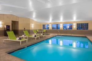 una piscina in una camera d'albergo con sedie verdi e una piscina di La Quinta Inn & Suites by Wyndham Las Vegas Nellis a Las Vegas