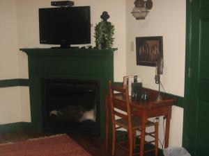 a living room with a fireplace with a television on top at The Brafferton Inn in Gettysburg