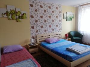 1 dormitorio con 2 camas y silla verde en MV Apartamenty Komfort, en Augustów