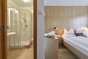 y baño con cama, ducha y lavabo. en Panoramahotel Obkircher en Nova Ponente