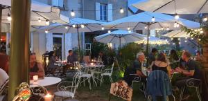 a group of people sitting at tables under umbrellas at La Villa du 15 - Chambres ind&eacute;pendantes & autonomes du restaurant La Maison - clim et piscine chauff&eacute;e - Lit King Size in Les Eyzies-de-Tayac