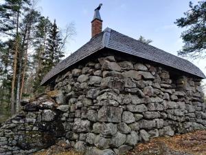 a stone building with a chimney on top of it at Rooms at Ellivuori in Karkku