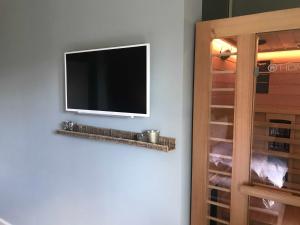 einen Flachbild-TV an einer Wand neben einem Schrank in der Unterkunft Schippers Butz strandnah mit Whirpool in Ostseebad Karlshagen