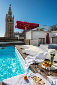 una piscina dell'hotel con tavolo e ombrellone di Cathedral Luxury Studio, Swimming Pool and Cathedral Views a Siviglia