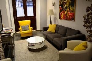 a living room with a black couch and yellow chairs at Hotel Alda Vía León in León