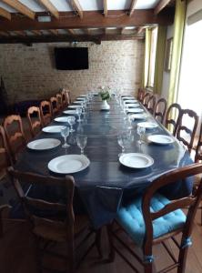 - une longue table avec des assiettes et des verres à vin dans l'établissement Domaine du Clos de la Touche Parc et Piscine, à Chaunay