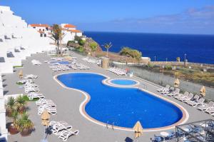 a resort with a pool and chairs and the ocean at Occidental Roca Negra - Adults Only in Agaete