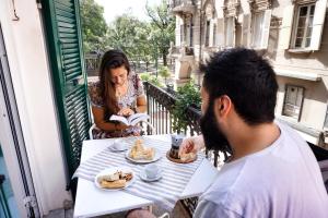 Ein Mann und eine Frau sitzen an einem Tisch mit Essen in der Unterkunft Grand Hostel Manin in La Spezia