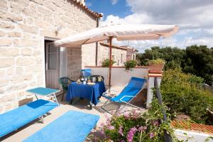 eine Terrasse mit einem Tisch, einem Sonnenschirm und Stühlen in der Unterkunft La Vignaredda - Residenza di Charme in Aggius