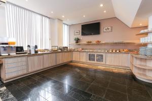 a large kitchen with a counter and a tv on the wall at Hotel Express Aeroporto in Porto Alegre