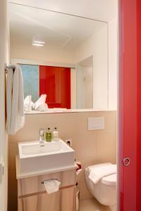 a bathroom with a toilet, sink, and bathtub at Hotel Platzhirsch in Zurich