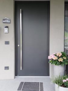 eine schwarze Tür eines Hauses mit Topfpflanze in der Unterkunft Appartement Mountainview in Saalbach-Hinterglemm