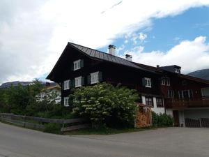 une maison noire et blanche avec un arbre dans l'établissement Alpenkönigin Fewo Lang, à Riezlern