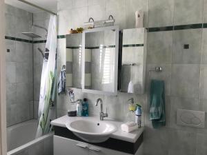 a bathroom with a sink and a mirror and a tub at Chambre d hôtes Le Petit Bonheur in Colombier