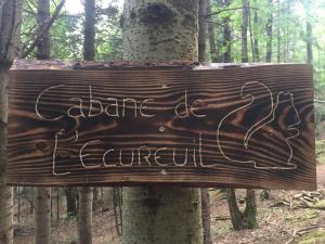 un cartel de madera en el bosque con escritura en él en cabane de l'Ecureuil, en Châtel-Guyon