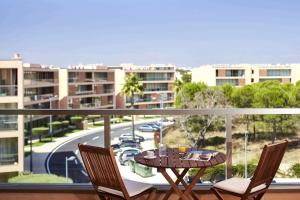 a balcony with a table and chairs and a view of a street at Apartamento T2 Herdade dos Salgados in Albufeira