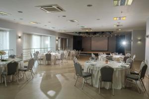 un salón de banquetes con mesas, sillas y una pantalla en Marins Park Hotel Novosibirsk, en Novosibirsk