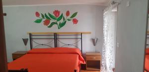 una camera da letto con un letto con una coperta rossa e un fiore sul muro di B&B Girasole a Colleferro