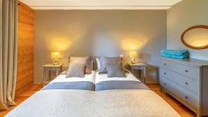 ein Schlafzimmer mit einem Bett mit zwei Nachttischen und einem Spiegel in der Unterkunft Les 360 - Apt 8 - BO Immobilier- remises sur les forfaits de skis Châtel ou Portes du soleil in Châtel