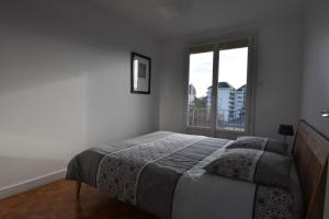 een slaapkamer met een bed en een groot raam bij chanteraine 2 in Reims