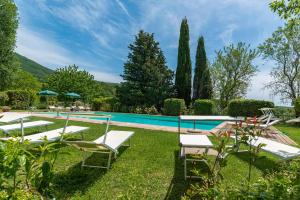 una piscina con sedie a sdraio e una piscina di Borgo Fastelli - House in historical Borgo in Tuscany - Quercia a Spineta