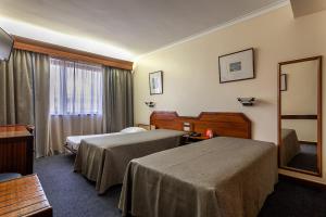 um quarto de hotel com duas camas e um espelho em Hotel Nacional em Lisboa